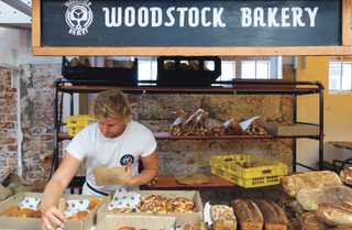 A baker picking out bread for a customer at a stall